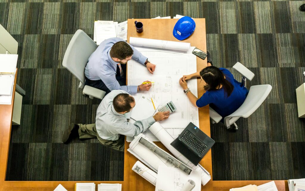 pexels-photo-416405-416405 Top view of a team working on construction plans in an office setting.